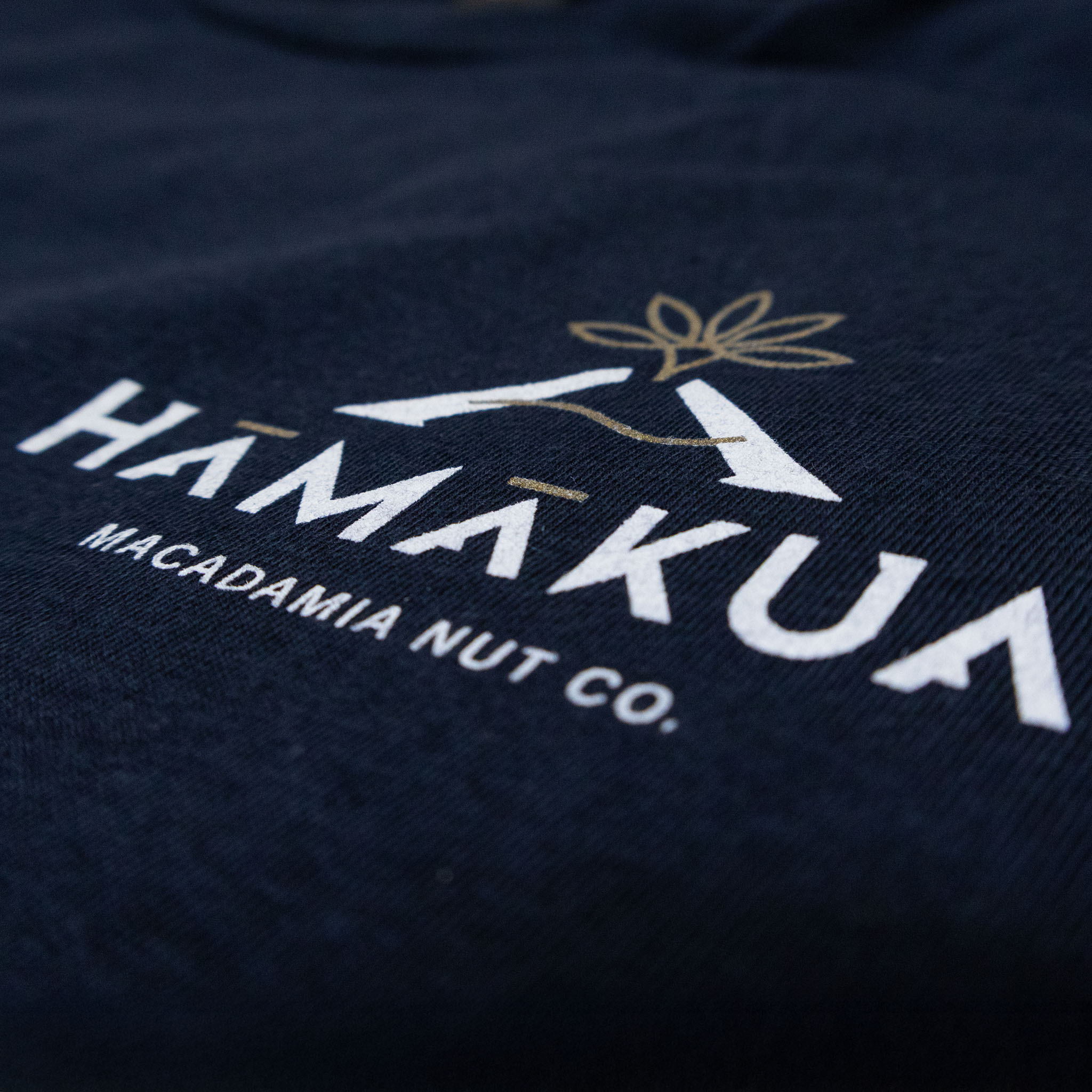 Close-up of a dark blue fabric with a Hāmākua Macadamia Nut Co. logo.