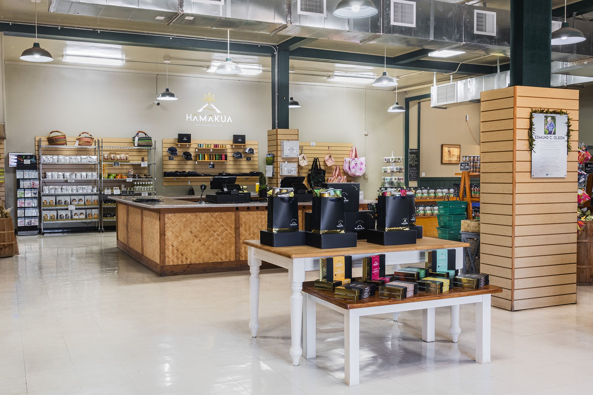 Visitor Center interior with wooden counters and product displays, featuring Hāmākua Macadamia Nut Co. logo.
