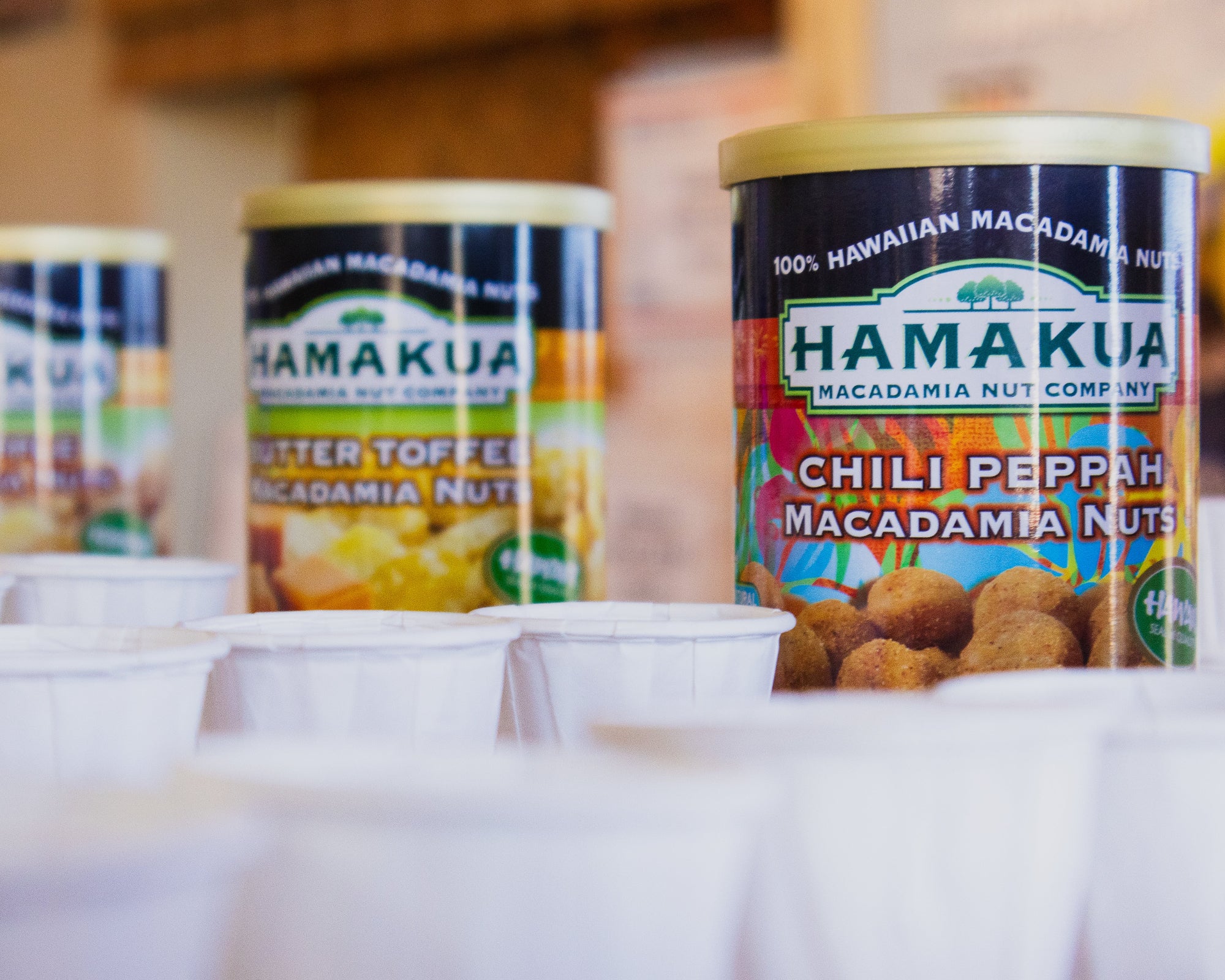 Three cans of Hamakua Macadamia Nuts behind samples offered at the Visitor Center